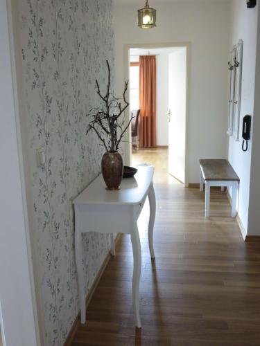 a white table with a vase on it in a hallway at Ferienwohnung Birkenflair in Seebruck