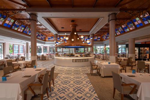 un ristorante con tavoli e sedie bianchi e un lampadario di Cordial Mogán Solaz a Puerto de Mogán