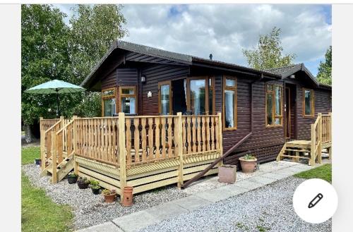 a small wooden cabin with a porch and an umbrella at Dot's Place 1 in Carnforth