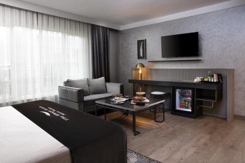 a hotel room with a bed and a couch and a television at The Wings Hotels Neva Palas in Ankara