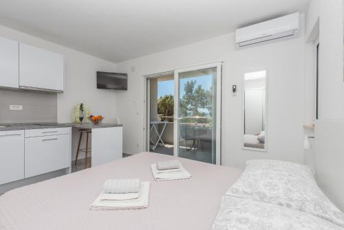 a white kitchen with a bed and a table at Apartments M&A in Makarska