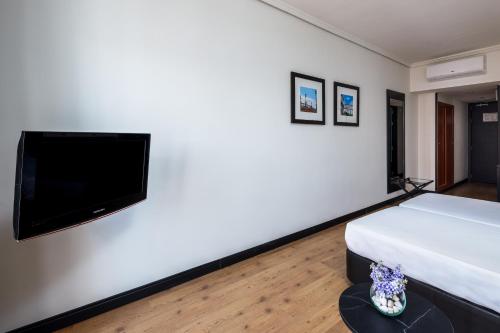 a bedroom with a bed and a flat screen tv at Virgen de los Reyes in Seville