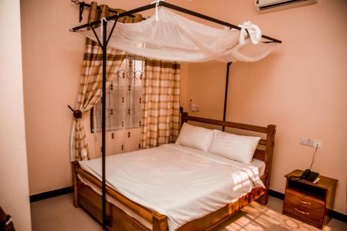 a bedroom with a four poster bed with a canopy at Randa Cottages Moshi in Kirua