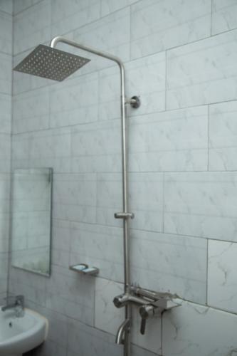 a bathroom with a shower with a sink and a mirror at Randa Cottages Moshi in Kirua