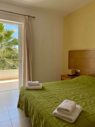 a bedroom with a green bed with towels on it at Manolis Apartments plakias in Plakias