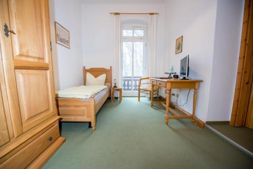 a bedroom with a bed and a desk with a computer at Bilz-Pension in Radebeul
