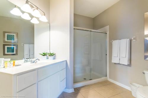 a white bathroom with a shower and a sink at Spacious Condo Near Convention Ctr & I-Drive, Pool in Orlando