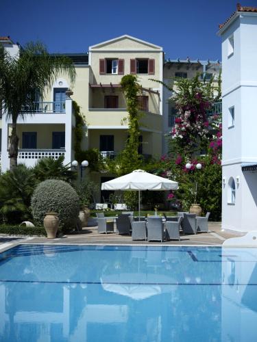 a pool with chairs and an umbrella and a building at Nikis Village in Poros