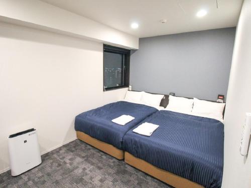 a bedroom with a blue bed and a window at HOTEL LiVEMAX Nagoya Kanayama in Nagoya