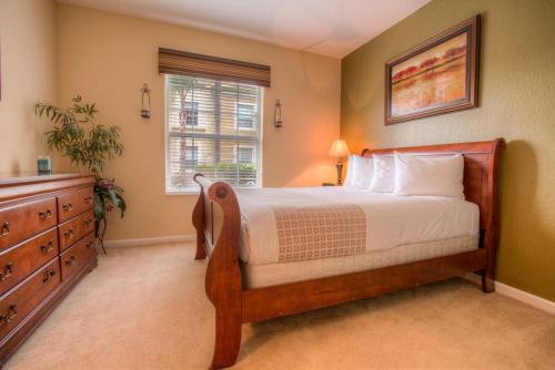 a bedroom with a bed and a dresser and a window at Stylish Condo at Vista Cay Resort Minutes to WDW in Orlando