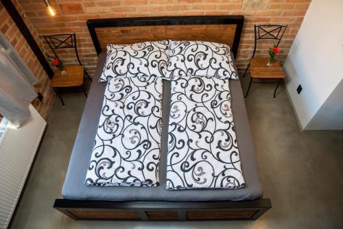 a bed with a black and white cover and two benches at Ecitlav - ubytování Valtice in Valtice