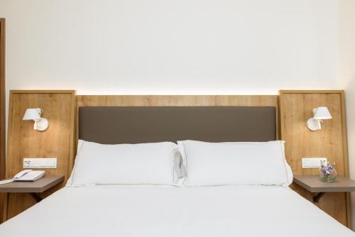a bedroom with a large white bed with two tables at Virgen de los Reyes in Seville