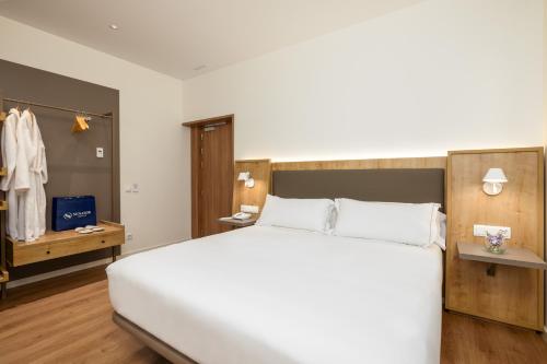 a bedroom with a large white bed and a closet at Virgen de los Reyes in Seville