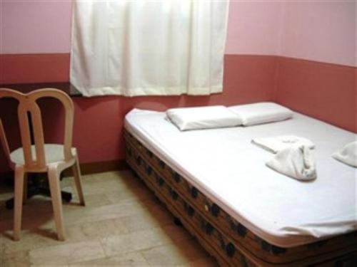 łóżko w pokoju z krzesłem i oknem w obiekcie GV Hotel - Cagayan de Oro w mieście Cagayan de Oro