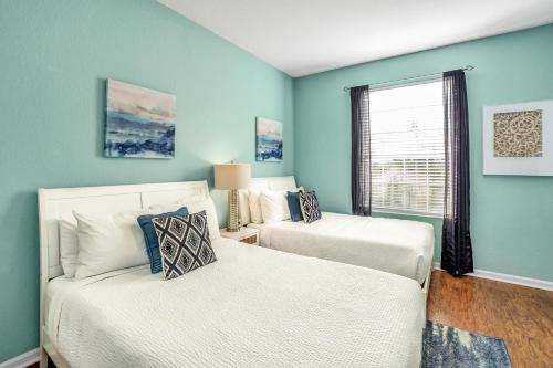 two beds in a room with blue walls and a window at Newly Updated Condo w Scenic Resort View in Orlando