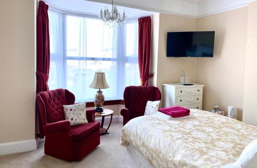 a bedroom with a bed and two chairs and a window at St. Georges House in Shanklin