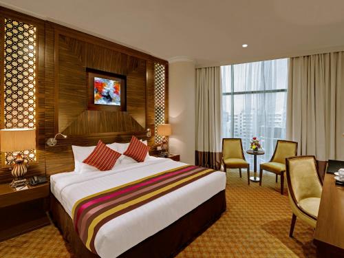 um quarto de hotel com uma cama grande e uma secretária em Landmark Premier Hotel em Dubai