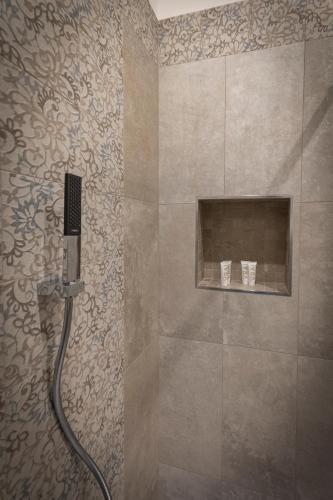 a shower with a hose in a bathroom with a wall at Al Duomo B&B in Amantea