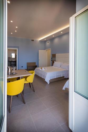 a bedroom with a bed and a table and yellow chairs at Al Duomo B&B in Amantea