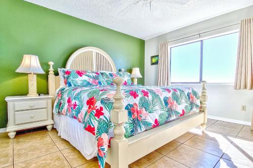 a bedroom with a bed with a floral bedspread at Beach Palms 406 in Clearwater Beach