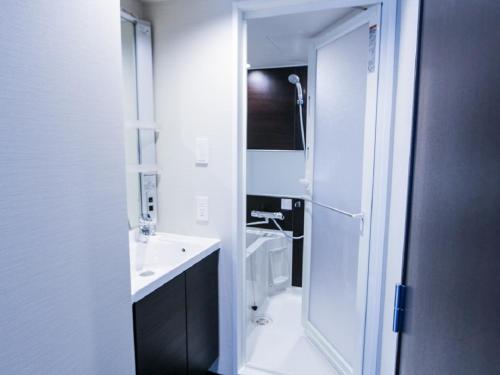 a white bathroom with a sink and a toilet at HOTEL LiVEMAX Yokohama Kannai Ekimae in Yokohama