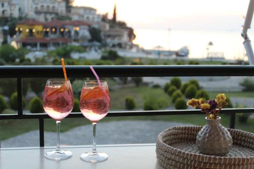 dos copas de vino sentadas en una mesa en un balcón en Fissas Rooms en Sivota