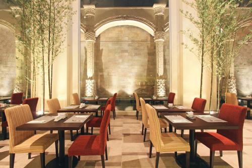 a restaurant with wooden tables and chairs and trees at Harmoni One Convention Hotel and Service Apartments in Batam Center