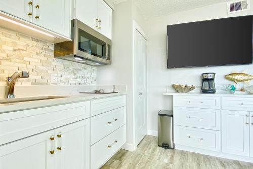 a kitchen with white cabinets and a tv on the wall at Belleair Beach Club 112 in Clearwater Beach