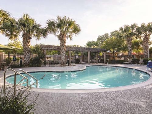 una piscina con palmeras en un complejo en La Quinta by Wyndham Austin Airport en Austin