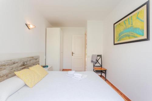 a bedroom with a white bed and a painting on the wall at Apartamento Bon Repos A7 in Cala'n Bosch
