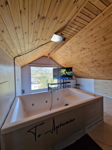 a large bath tub in a room with a wooden ceiling at Aprosmeno Jacuzzi House 2 in Agros