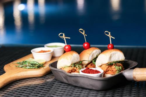 a tray of sandwiches with cherries and other foods at Mahagun Sarovar Portico Suites in Ghaziabad