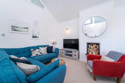 uma sala de estar com um sofá azul e duas cadeiras em Shearwater em Carbis Bay