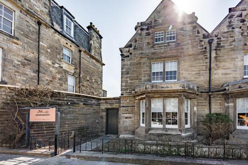an old brick building with a sign in front of it at No1 Apartments St Andrews - South Street in St. Andrews
