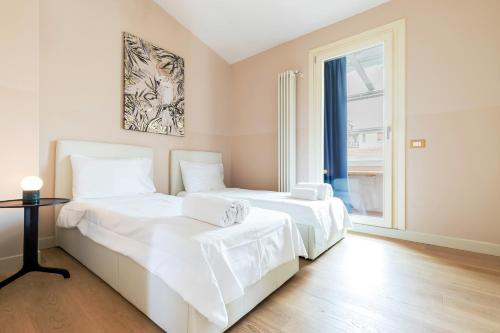 two beds with white sheets in a room with a window at Milan Retreats in Milan