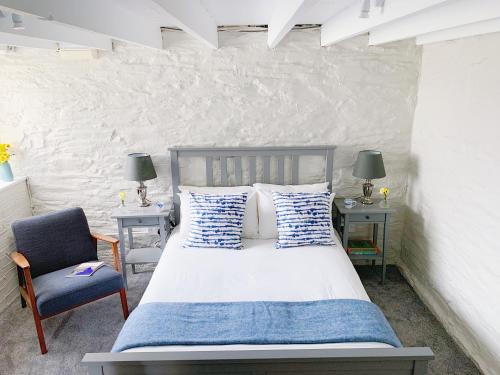 a bedroom with a bed and a blue chair at The Laurels Cottages nr Padstow and Wadebridge in Wadebridge