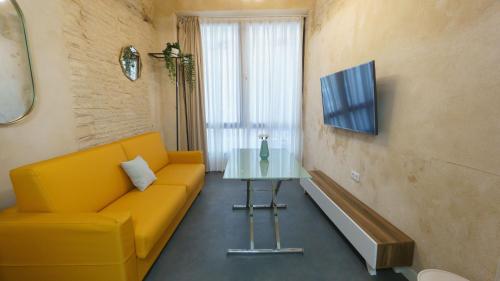 salon z żółtą kanapą i stołem w obiekcie RentalSevilla Cardenal Cervantes I w Sewilli