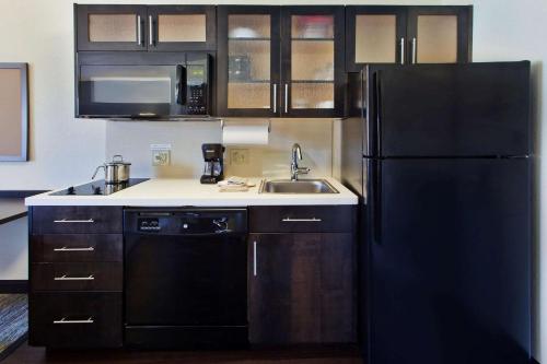 ウィチタにあるMainStay Suites - Wichita NEのキッチン(黒い冷蔵庫、シンク付)