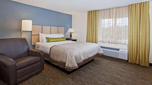 a bedroom with a bed and a chair and a window at MainStay Suites- Kansas City Overland Park in Overland Park