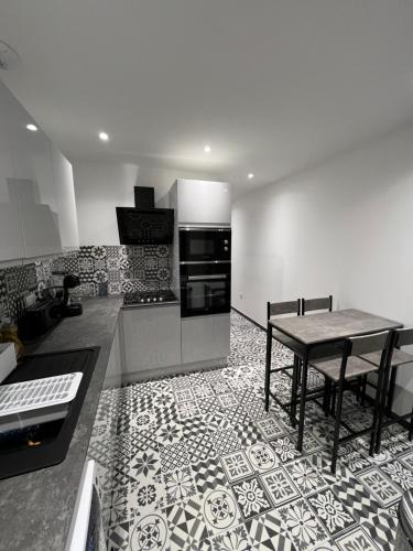 une cuisine avec une table et une cuisine avec un sol carrelé dans l'établissement Appartement haut de gamme avec Jacuzzi Champagnole, à Champagnole