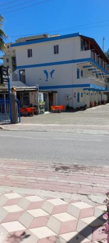 a large white building with orange tables in front of it at Rooms and Apartments Analipsi in Shëngjin