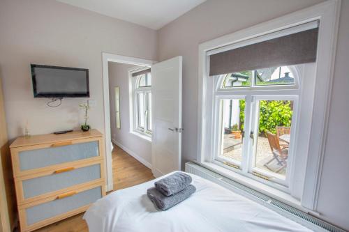 a bedroom with a bed and a window and a tv at Helena Cottage in Elie