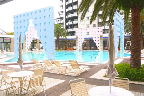 a pool with chairs and tables in a building at The Residential Suites Fukuoka in Fukuoka