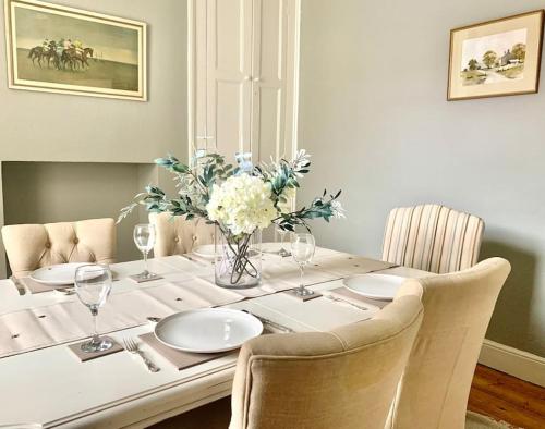 a dining room table with a vase of flowers on it at Lovely 3 bed house in the heart of Cheltenham in Cheltenham