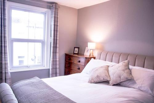 a bedroom with a white bed with a window at Lovely 3 bed house in the heart of Cheltenham in Cheltenham