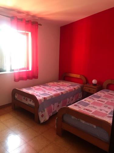 a bedroom with two beds and red walls at Casa dos Pais in Odeceixe