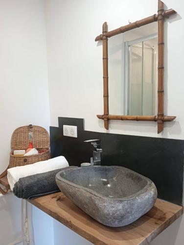 une salle de bain avec un lavabo en pierre et un miroir dans l'établissement Escapade de charme les pieds dans l'eau, à Houlgate