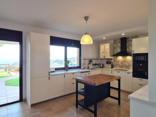 a kitchen with white cabinets and a wooden table at VILLA LA CALA with swimming pool & sea view, 10 min walk from the sea in Blanes