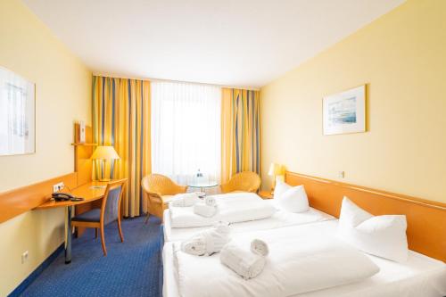 a hotel room with two beds and a desk at Arkona Strandhotel in Binz