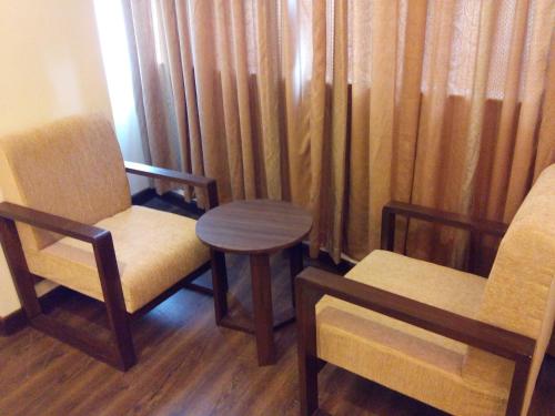 a room with two chairs and a table and curtains at Hotel Regal Airport in Kathmandu